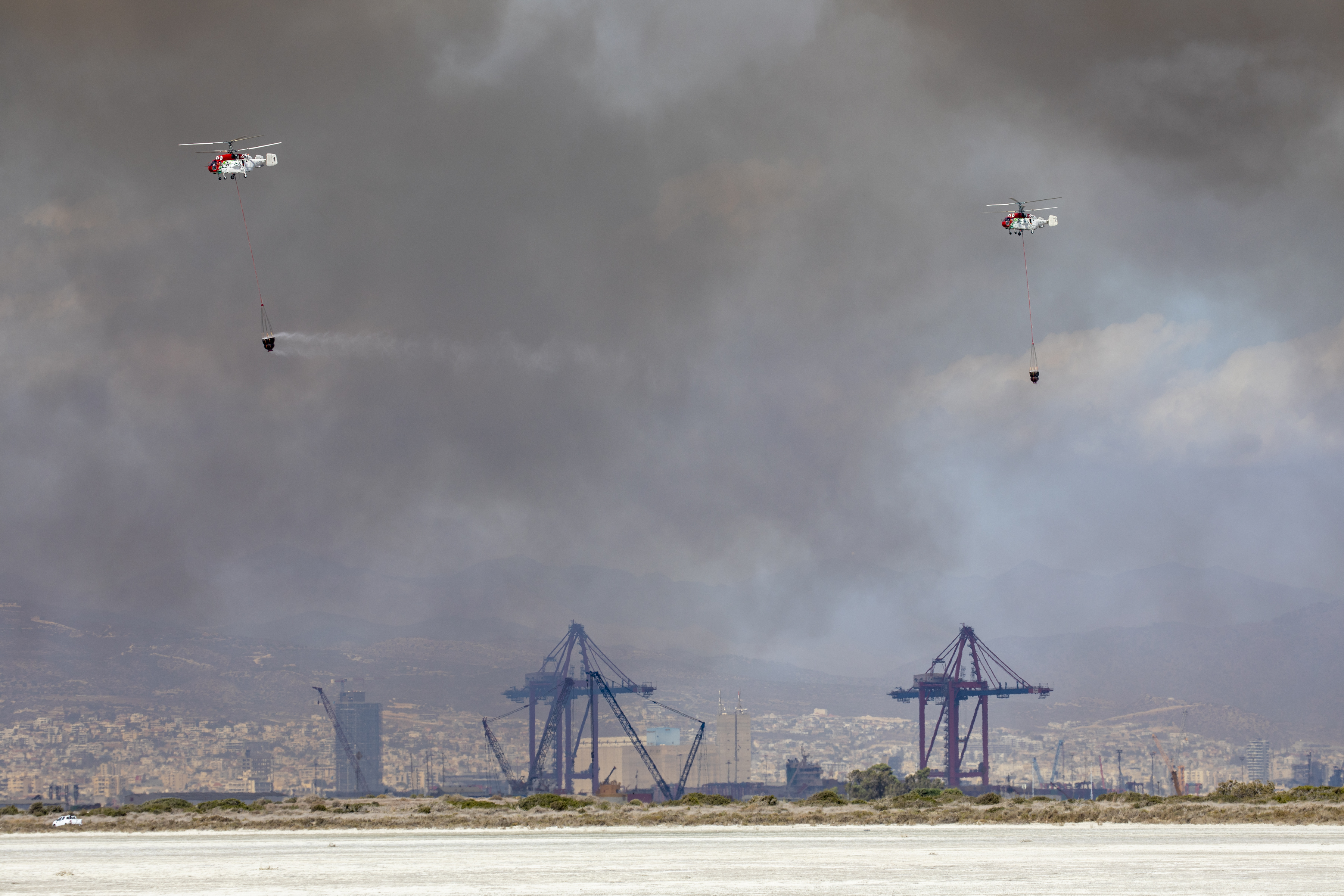 Image shows two helicopters dropping water from under sling